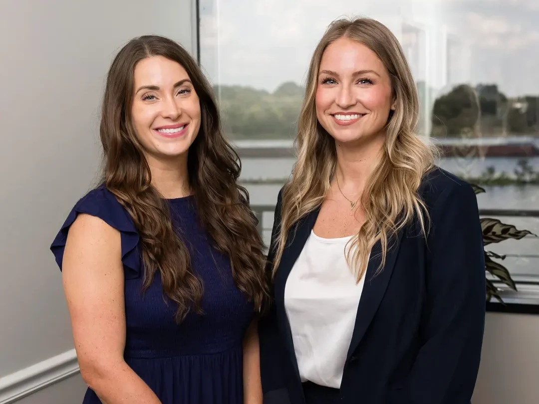 Sara Hanle and Brittani Reynolds of TMB client service at the Cottondale Lane office, with the Arkansas River behind them